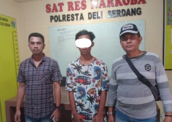 Diapit 2 Personel: Tersangka pengedar sabu AGS diapit Personel, saat diserahkan ke Satres Narkoba Polresta Deliserdang. Foto: Dok. Istimewa.