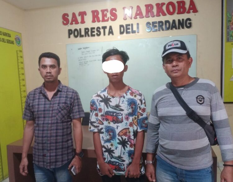 Diapit 2 Personel: Tersangka pengedar sabu AGS diapit Personel, saat diserahkan ke Satres Narkoba Polresta Deliserdang. Foto: Dok. Istimewa.